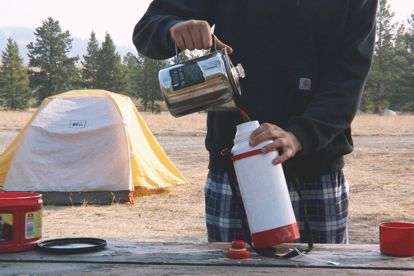 pouring coffee into a vintage thermos while camping
